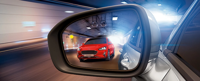 Rode auto verschijnt in de dode hoek van de bestuurder, waarop het dodehoekdetectiesysteem wordt geactiveerd.
