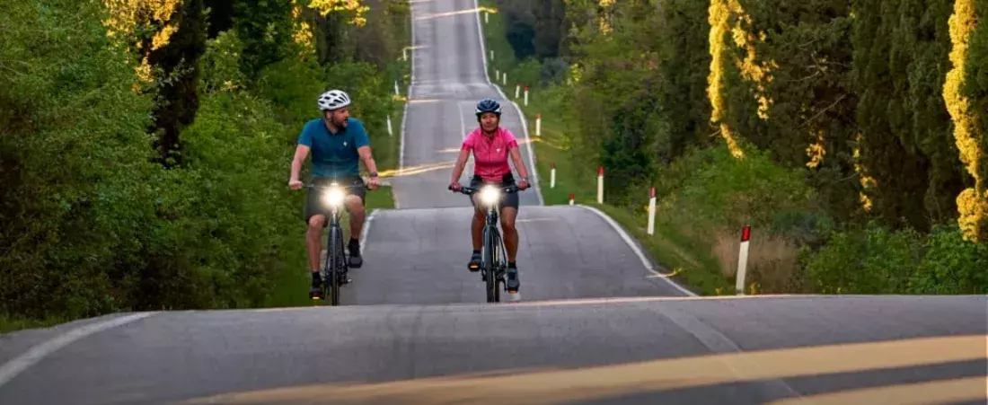 Toerfietsers met verlichting op heuvelachtige weg