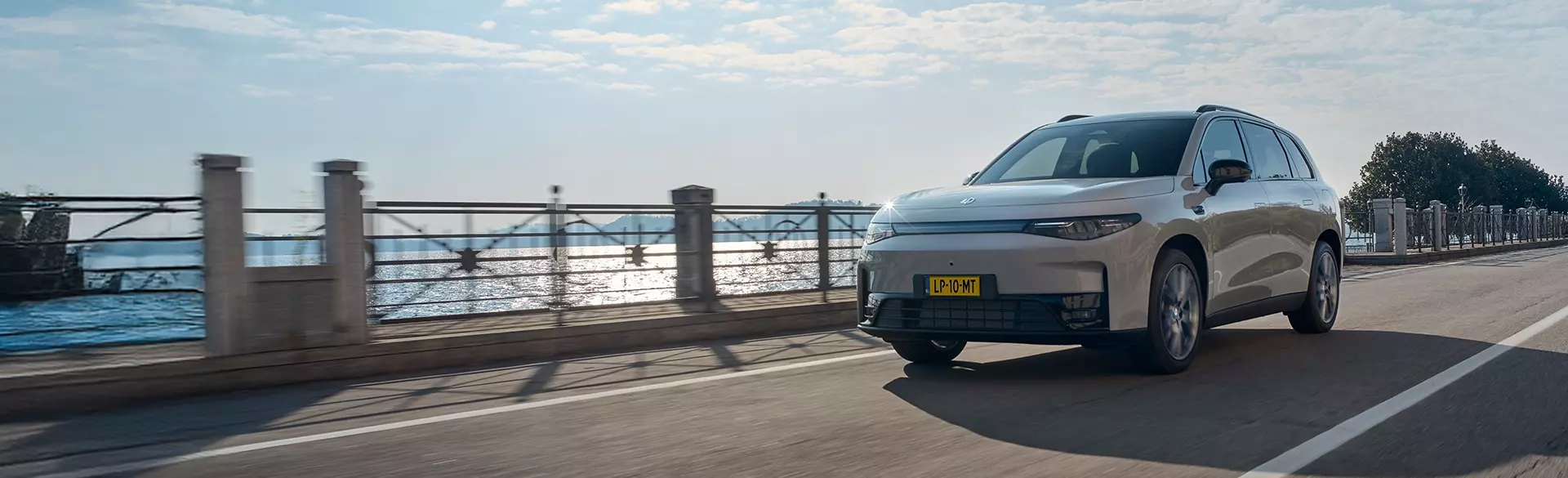 Brede sfeerafbeelding met een rijdende Leapmotor C10 Hybrid EV rechts uitgelijnd